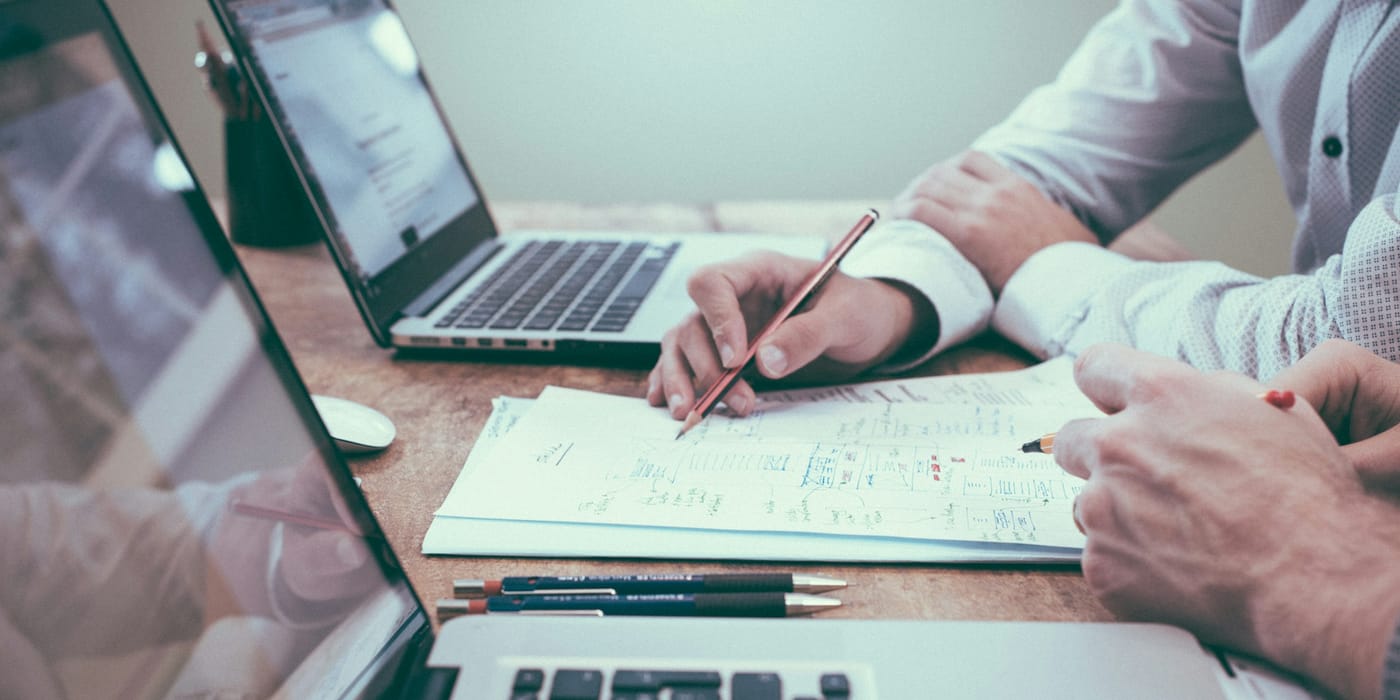 A finance lead comparing IT staffing and managed service costs on a desk of documents